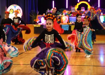 A vibrant Day of the Dead dance performance featuring dancers in colorful costumes and traditional skull makeup.
